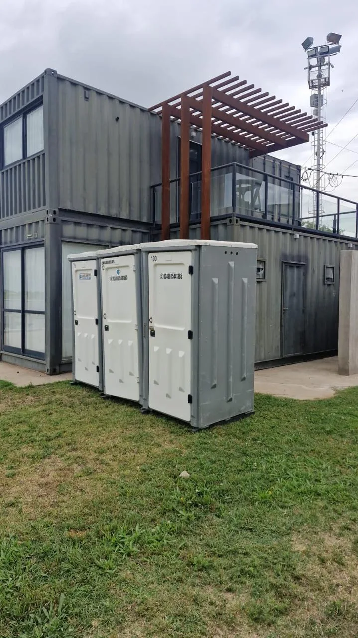 Tres baños químicos instalados junto a un espacio de trabajo modular