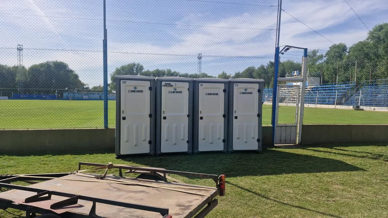 Cuatro baños químicos instalados junto a un campo deportivo